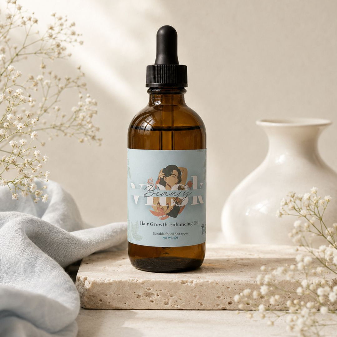 An amber glass dropper bottle of Beauty by Vivienne Hair Growth Enhancing Oil sits on a stone slab, surrounded by dried baby's breath flowers, a light blue cloth, and a white ceramic vase against a warm beige background.